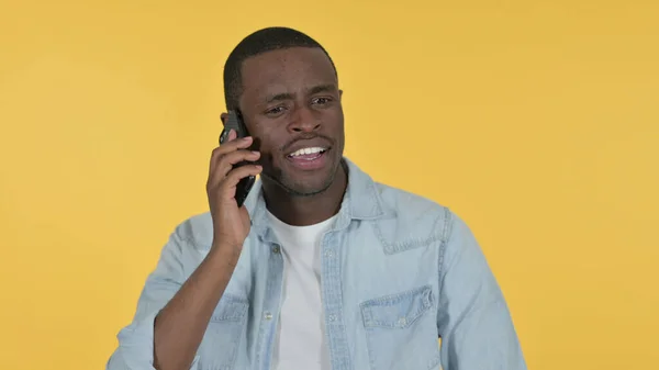 Joven africano hablando en Smartphone, fondo amarillo —  Fotos de Stock