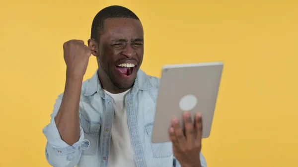 Joven africano celebrando en la tableta, fondo amarillo —  Fotos de Stock