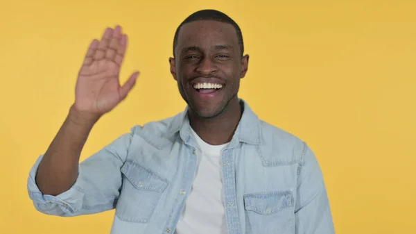 Saludando al joven africano ondeando, fondo amarillo — Foto de Stock