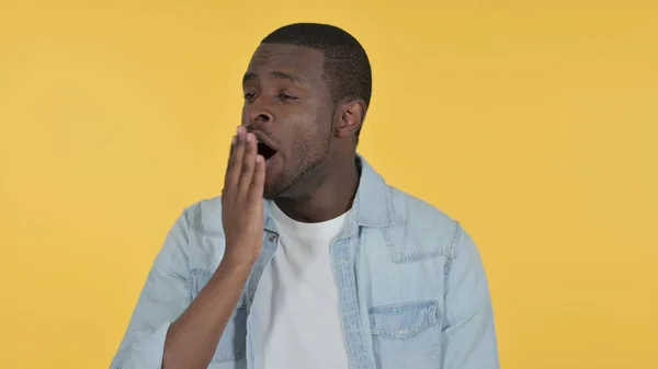 Joven africano soñoliento bostezando, fondo amarillo — Foto de Stock