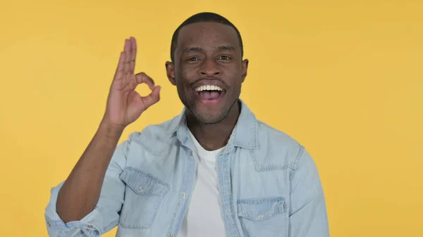 Junger Afrikaner mit OK-Zeichen, gelbem Hintergrund — Stockfoto