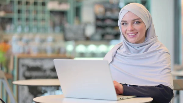 Cheerful Young Arab Woman with Laptop Smiling at Camera