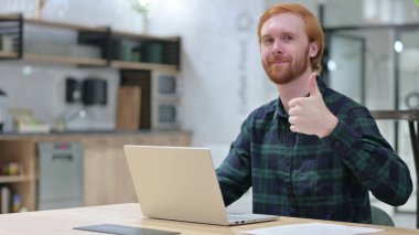 Dizüstü bilgisayarlı pozitif kızıl adam Başparmaklarını Yukarı Gösteriyor