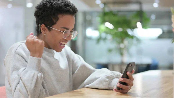 Junge Afrikanerin feiert Erfolg per Smartphone — Stockfoto