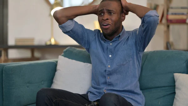 Joven africano teniendo pérdida en videojuego en sofá —  Fotos de Stock