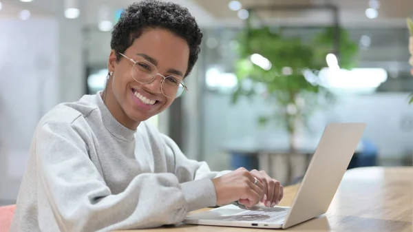 Ung afrikansk kvinna med bärbar dator ler mot kameran — Stockfoto