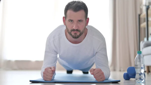 Young Man Doing Plank on Yoga Mat at Home, Frontal View — Stockfoto