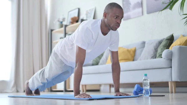 Afrikai férfi fekvőtámaszt csinál a jóga matracon otthon — Stock Fotó