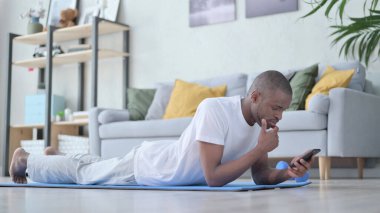 Egzersizden sonra akıllı telefon kullanan Afrikalı adam.