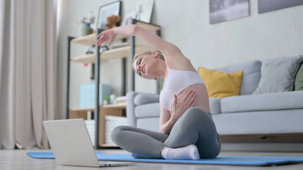 Mujer haciendo yoga mientras está en videollamada en el ordenador portátil —  Fotos de Stock