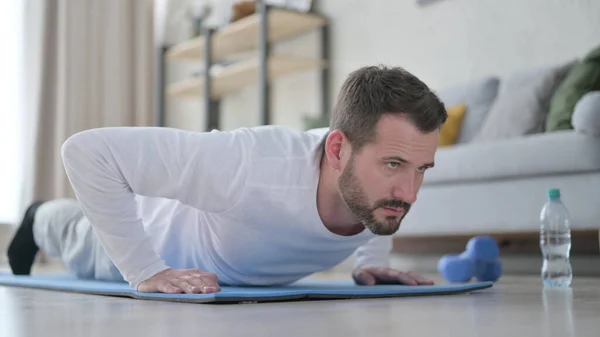 Közelkép az érett felnőtt férfiról, aki fekvőtámaszozik a jóga matracon otthon — Stock Fotó