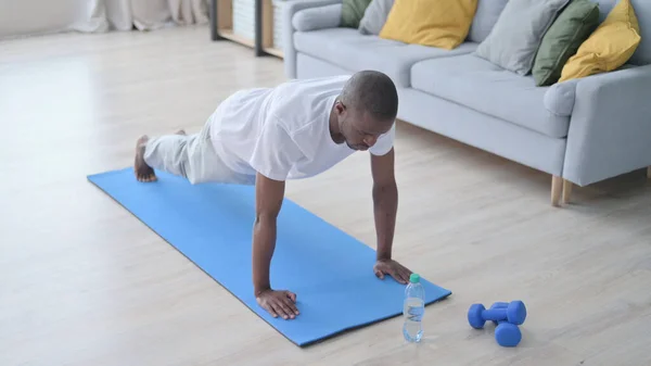 Afrikai férfi fekvőtámaszt csinál a jóga matracon otthon — Stock Fotó