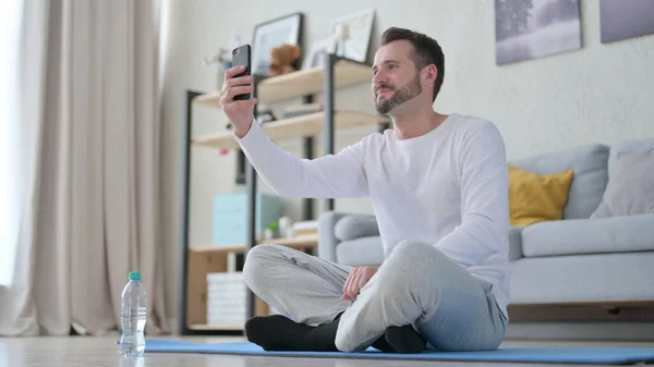 Hombre adulto maduro hablando en videollamada en Smartphone en Yoga Mat —  Fotos de Stock