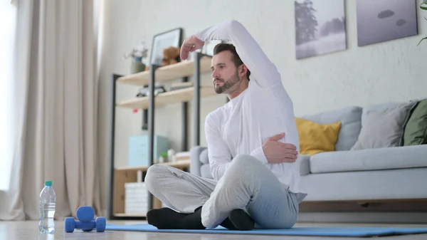 Felnőtt férfi nyújtózkodik a jóga matracon otthon — Stock Fotó
