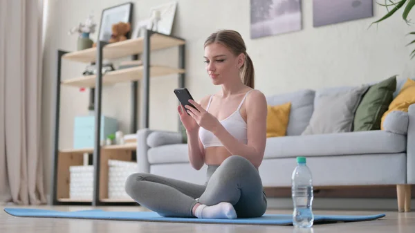 Mujer usando Smartphone en Estera de Yoga en Casa —  Fotos de Stock