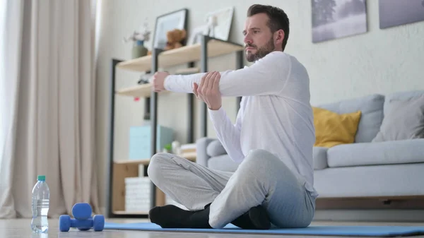 Hombre adulto maduro haciendo estiramientos en la esterilla de yoga en casa —  Fotos de Stock
