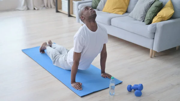 Hombre africano haciendo alza frente a la postura del perro en la estera de yoga —  Fotos de Stock