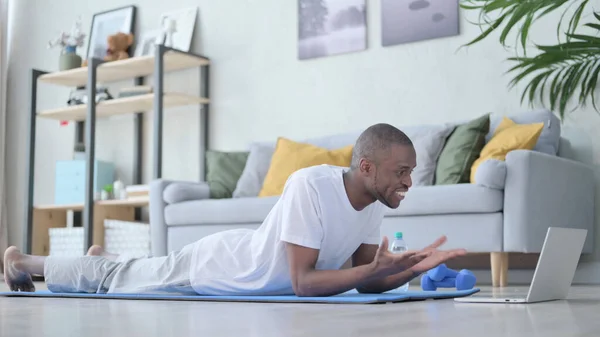 Afrikai férfi beszél videohíváson Laptopon, miközben a jóga matracon — Stock Fotó