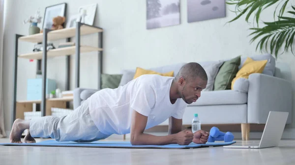 Afrikai férfi deszkázik a jóga matracon otthon — Stock Fotó