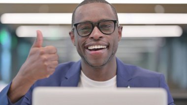 Dizüstü bilgisayarlı Genç Afrikalı İşadamı Başparmağını kaldırdı