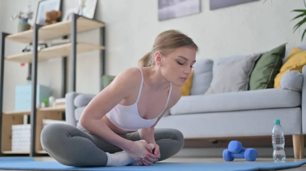 Mulher fazendo alongamentos no tapete de ioga em casa — Fotografia de Stock
