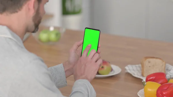 Uomo che utilizza lo schermo verde Smartphone in cucina — Foto Stock