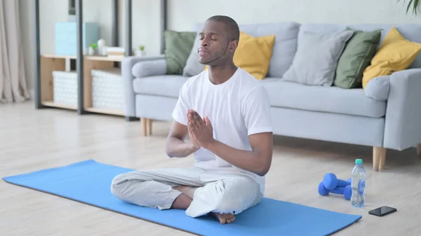 Meditar al hombre africano sentado en la esterilla de yoga —  Fotos de Stock