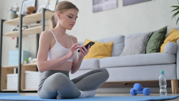 Mujer usando Smartphone en Estera de Yoga en Casa —  Fotos de Stock