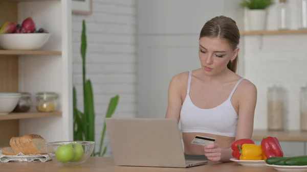 Женщина делает онлайн покупки на ноутбуке в кухне — стоковое фото