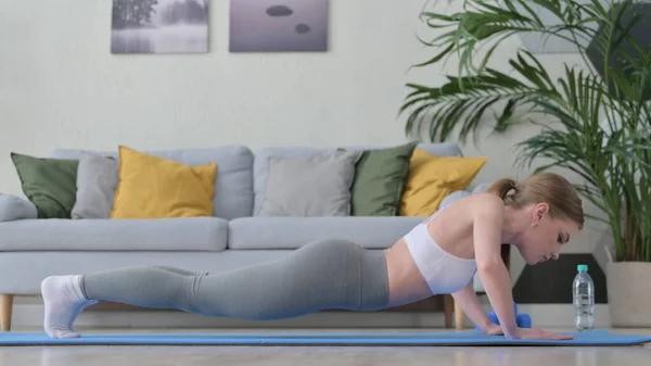 Mujer trabajadora haciendo flexiones en la esterilla de yoga en casa — Foto de Stock