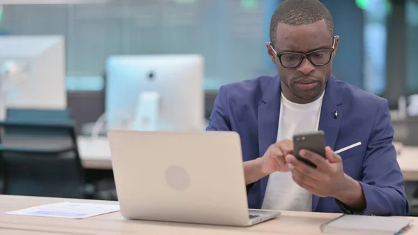 Joven empresario africano usando Smartphone en la oficina —  Fotos de Stock