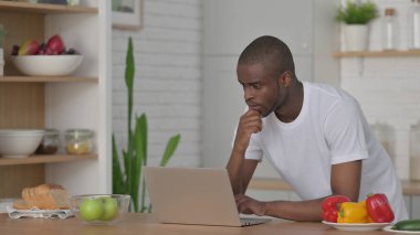 Mutfakta dizüstü bilgisayarda çalışan Afrikalı adam. 