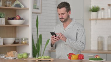 Mutfakta Yemek Yaparken Akıllı Telefon Kullanan Adam