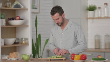 Pijamalı adam Mutfakta Salatalık soyuyordu 