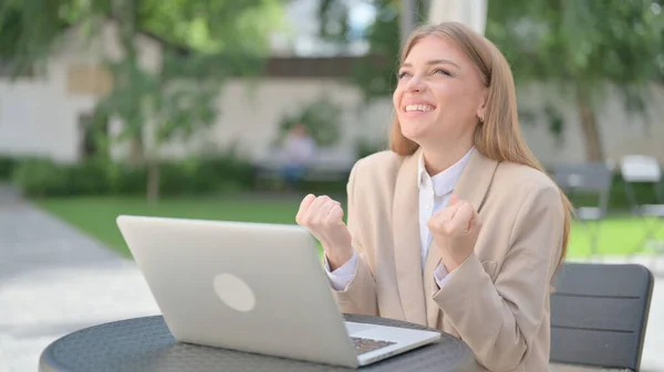 Mujer de negocios celebrando el éxito en el ordenador portátil en el café al aire libre —  Fotos de Stock