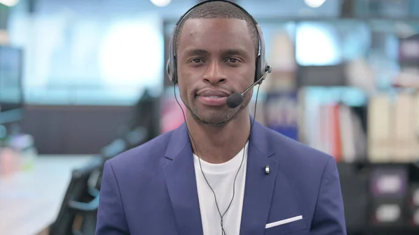 Retrato de un joven empresario africano con auriculares mirando a la cámara —  Fotos de Stock