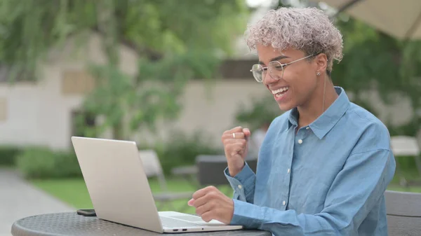 Afrikansk kvinna firar framgång på laptop i Outdoor Cafe — Stockfoto