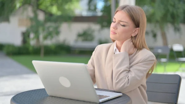 Donna d'affari con computer portatile con dolore al collo in Outdoor Cafe — Foto Stock