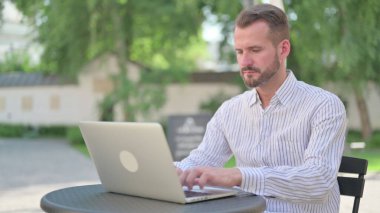 Olgun Yetişkin Adam açık kafede dizüstü bilgisayarda çalışıyor. 