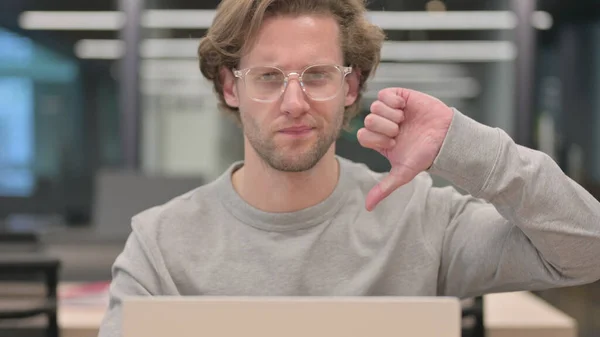 Retrato de polegares para baixo por homem com laptop no escritório — Fotografia de Stock