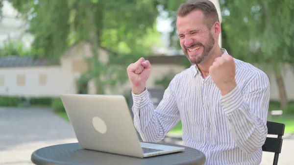 Pomyślny Dorosły Dorosły Mężczyzna świętuje na laptopie w Outdoor Cafe — Zdjęcie stockowe