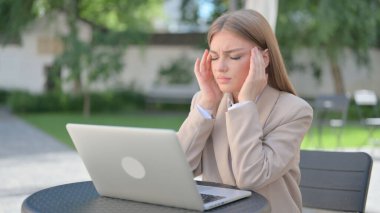Laptop 'u olan iş kadını açık kafede baş ağrısı çekiyor. 
