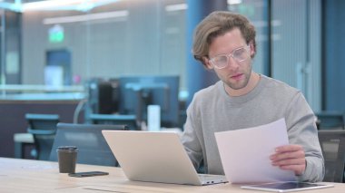 Dizüstü bilgisayarlı Genç Adam Belgelerde Başarı Kutlaması