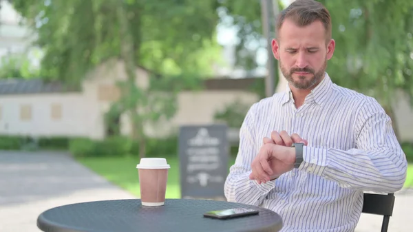 Mature Adult Man using Smartwatch in Outdoor Cafe — Stockfoto