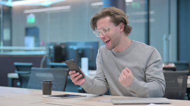 Ofisteki Akıllı Telefon 'da Başarıyı Kutlayan Genç Adam