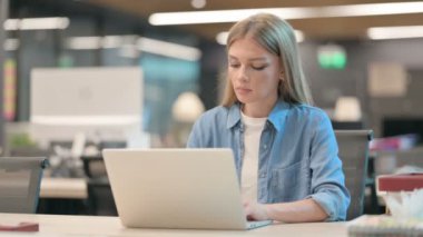 Ofiste dizüstü bilgisayar kullanırken Kameraya Bakan Kadın