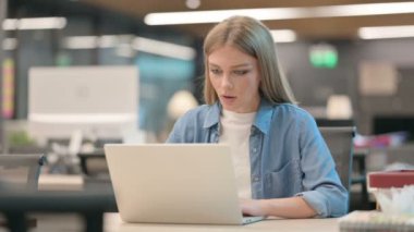 Ofiste dizüstü bilgisayar kullanırken kutlama yapan genç kadın