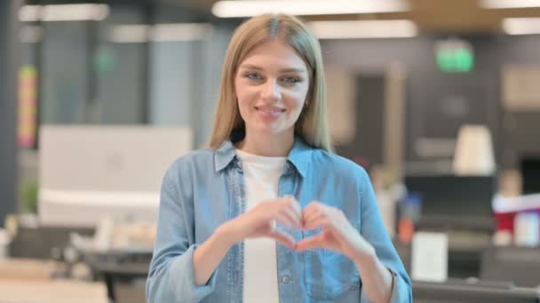 Молодая женщина показывает знак сердца от руки — стоковое видео