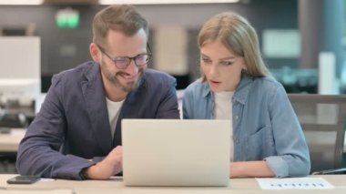 Orta yaşlı adam ve genç kadın dizüstü bilgisayar kullanırken beşlik çakıyor 
