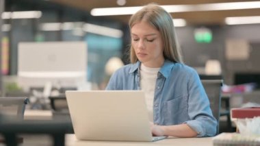 Ofiste dizüstü bilgisayar kullanırken sırt ağrısı çeken kadın